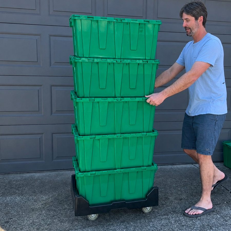 Owner rolling a stack of five green moving totes on a dolly in his driveway